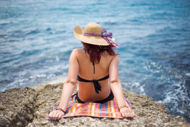 Bir genç kız bir bikini ve sahilde bir hasır şapka sahiptir