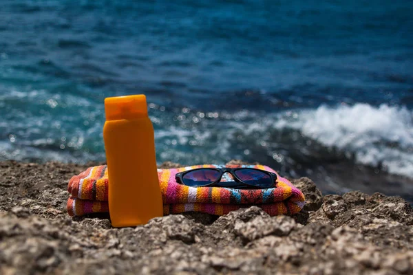 Літо, синє море, пляжний рушник, сонцезахисний крем і окуляри — стокове фото