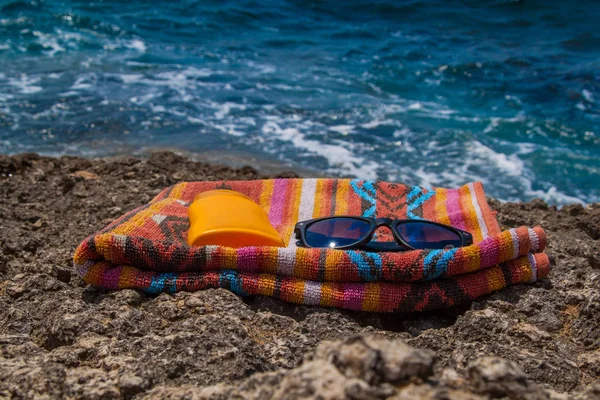 Verano, mar azul, toalla de playa, protector solar y gafas — Foto de Stock