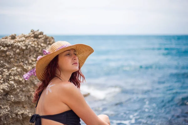 Une jeune fille sur une plage avec un chapeau, soleil et jouit du soleil, sur t — Photo