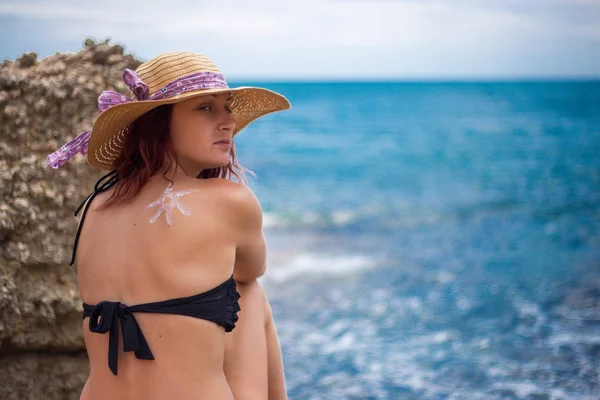 Uma menina em uma praia com um chapéu, sol e goza do sol, em t — Fotografia de Stock