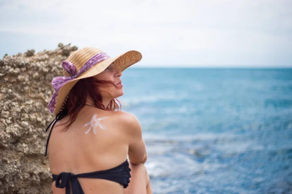 En ung flicka på en strand med en hatt, sol och har solen, på t — Stockfoto