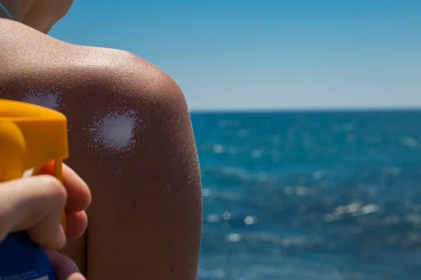 Aplicando protetor solar de creme solar em um ombro de uma mulher para tanino — Fotografia de Stock