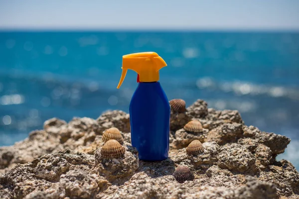 Crema solar protector solar para el bronceado de pie en las rocas de la playa en un d soleado — Foto de Stock