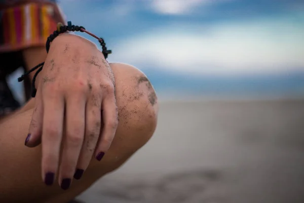 Девушка, сидящая на пляже, фокусируется на руке и колене. Овьедо — стоковое фото