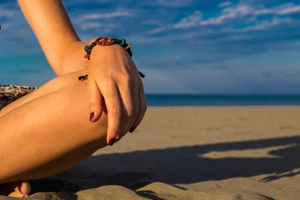 Женщина сидит на пляже с крупным планом руки с браслетом и — стоковое фото