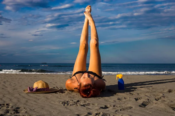 Jonge knappe gelooid roodharige opleggen aan een zandstrand met een — Stockfoto