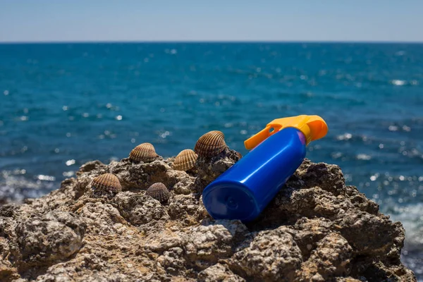 Crema solar protector solar primer plano que pone en las rocas de la playa con el sueño — Foto de Stock