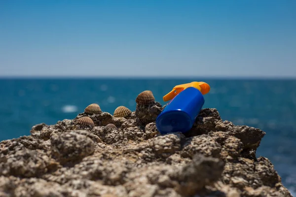 Crema solar puesta en las rocas celestiales de la playa con mar y azul s — Foto de Stock