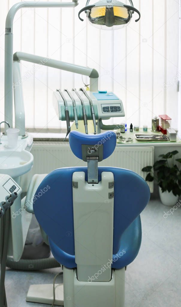 Blue and white dentist chair with sink and dentist equipment too