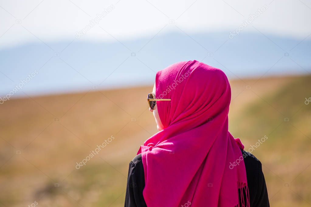 Covered muslim caucasian girl with pink hijab and standing on a 