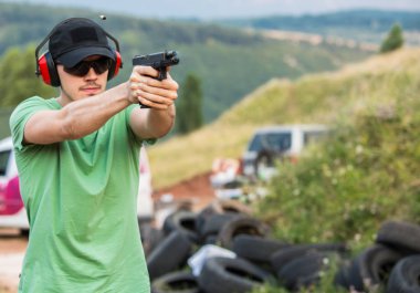 Yakışıklı genç adam silahla uzak hedefe yönelik 