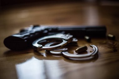 Police equipment handcuffs and black pistol on the wooden backgr clipart