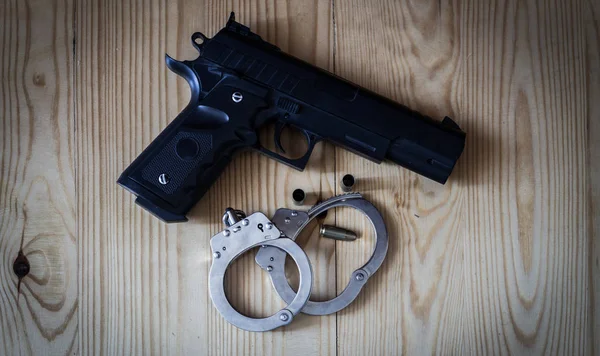 Black pistol gun with silver handcuffs and golden bullet shells