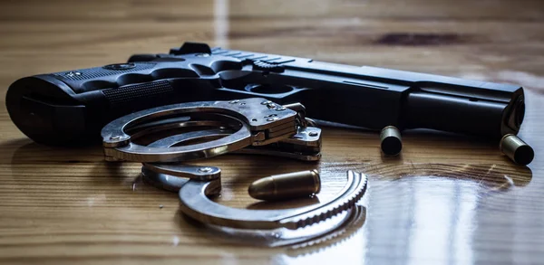 Closeup of silver handcuffs with golden bullet shells with gun p