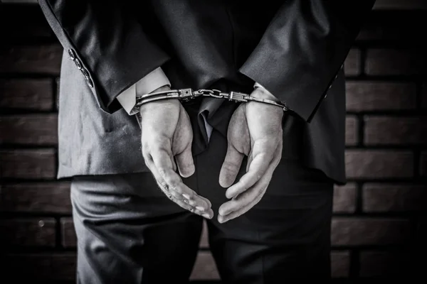 Бизнесмен и его руки на спине в наручниках из-за преступности — стоковое фото
