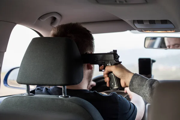 Um ladrão, um criminoso com uma ameaça de pistola, tenta roubar um carro , — Fotografia de Stock
