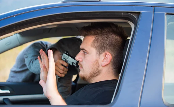 A thief, a criminal with a pistol threat, tries to steal a car, — Stock Photo, Image