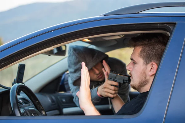Bir hırsız, bir suçlu bir tabanca tehdidiyle bir araba çalmak için çalışır, — Stok fotoğraf