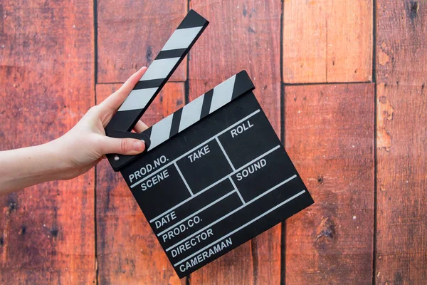 Clapper plates, women's hands and film clapper on a wooden backg — Stock Photo, Image