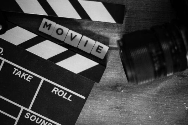 Movie clapper and old camera on a wooden background, movie shoot