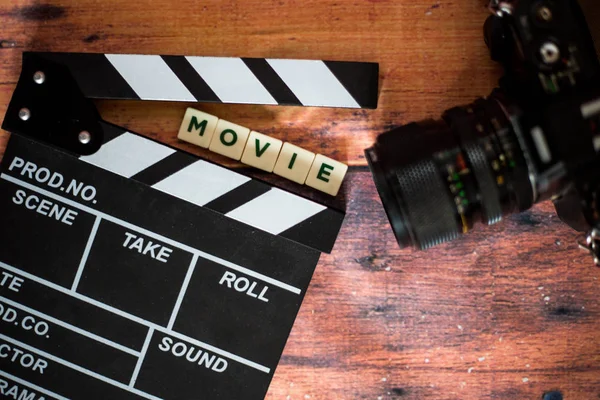 Киноаплодисменты и старая камера на деревянном фоне, съемки фильмов — стоковое фото