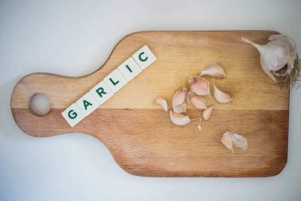 Garlic on wooden cutting board, shallots spread with word garlic