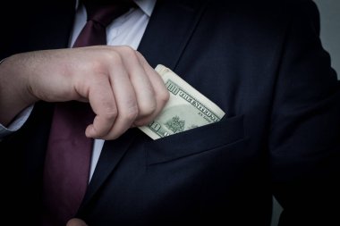 Bir işadamı, nakit toplamını gösterir takım elbise cebine koyar