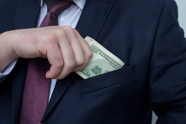 Ένας επιχειρηματίας δείχνει ένα ποσό των μετρητών, το βάζει στην τσέπη του κοστούμι — Φωτογραφία Αρχείου