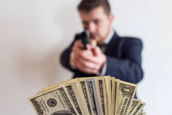 Ένας κλέφτης σε ένα κοστούμι με ένα πυροβόλο όπλο που απευθύνεται σε ένα άτομο παίρνει μετρητά, hundr — Φωτογραφία Αρχείου