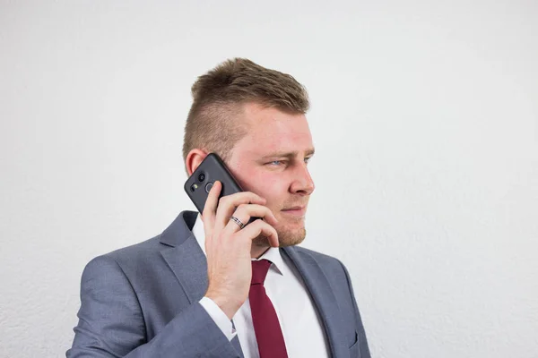 Молодой бизнесмен в костюме, разговаривает по мобильному телефону, устраивает — стоковое фото