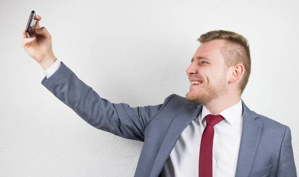 A young businessman in a suit, using a front camera of a mobile — Stock Photo, Image