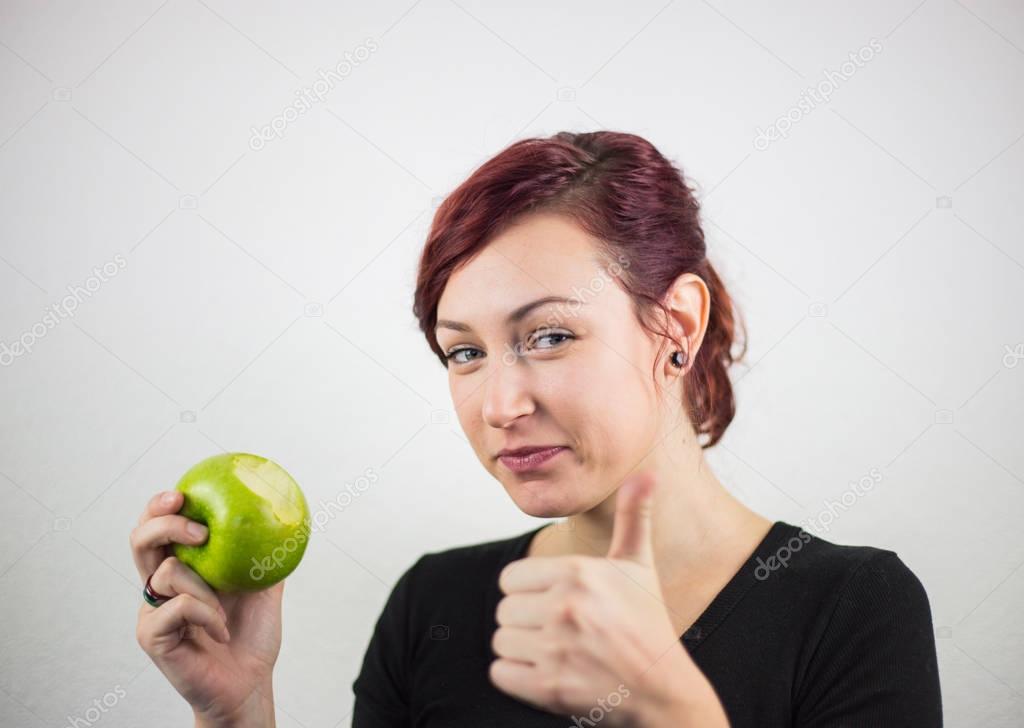 A young girl holds a battered apple in her hand, with a smile on