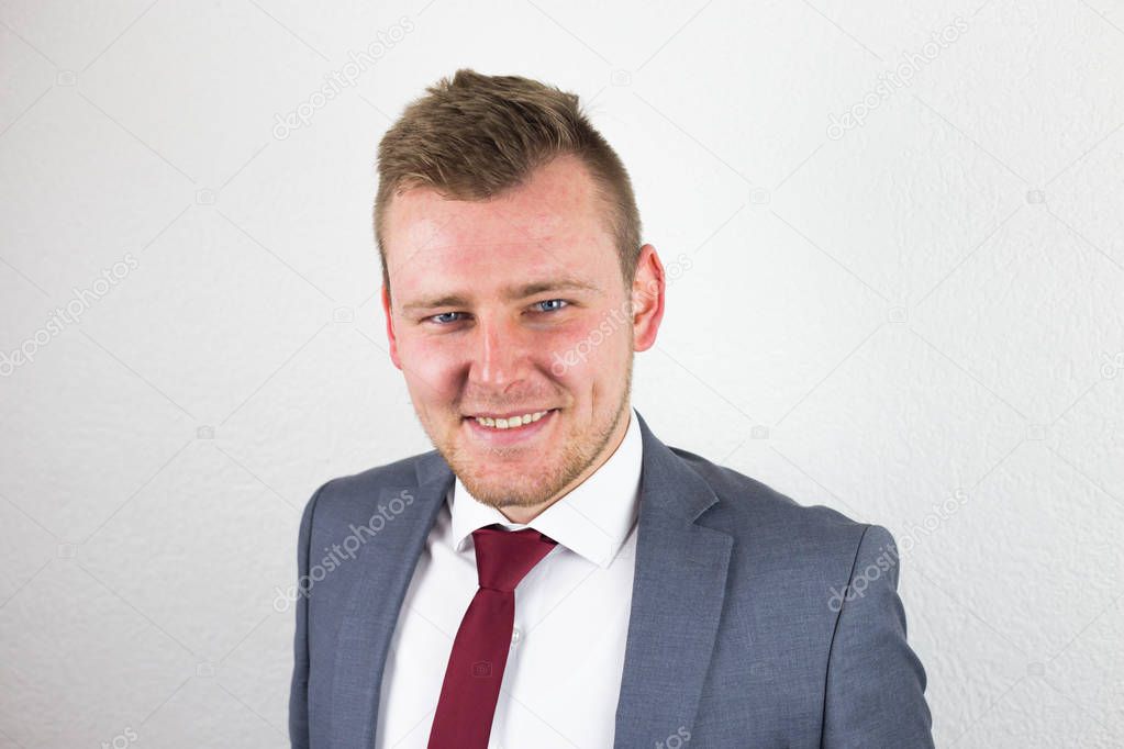 A young businessman in a suit, with a smile on his face, a white
