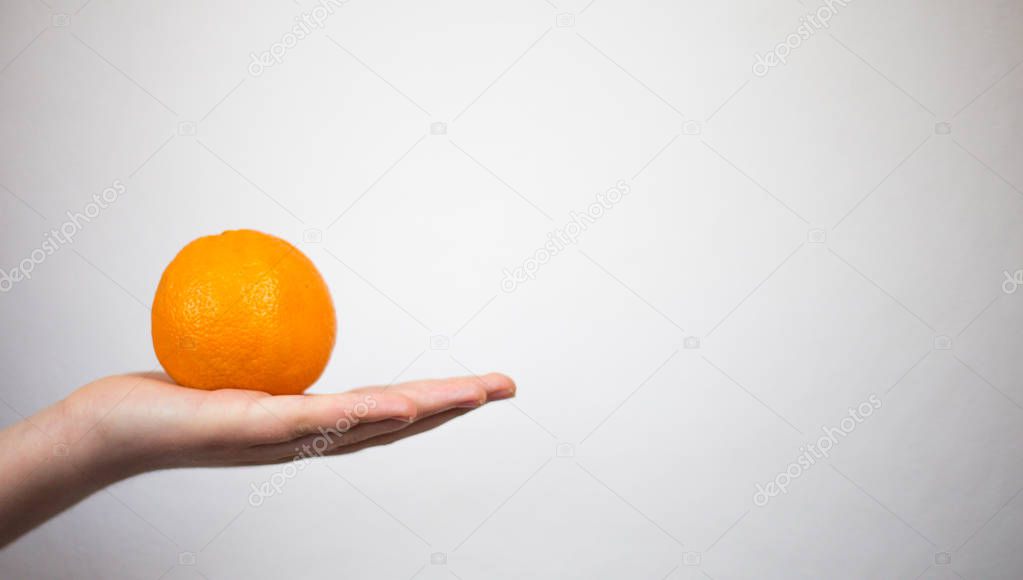 Closeup of hand holding an orange with white background and givi
