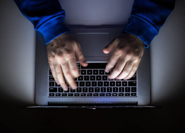 Киберпреступник, хакер с ноутбука, пишет коды доступа к несанкционированному
