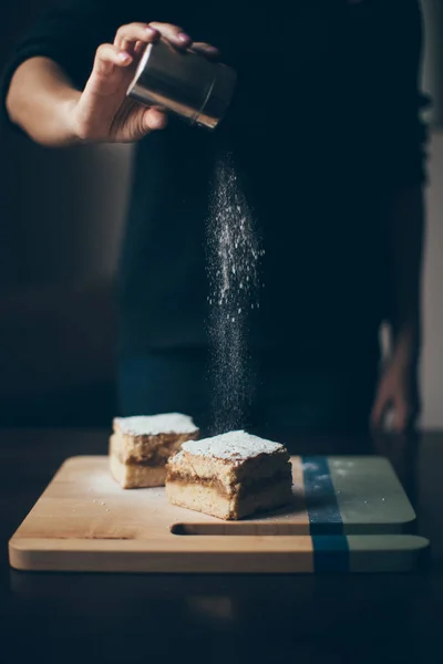 Γυναίκα καταιονισμό κέικ με ζάχαρη άχνη — Φωτογραφία Αρχείου
