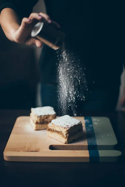 Γυναίκα καταιονισμό κέικ με ζάχαρη άχνη — Φωτογραφία Αρχείου