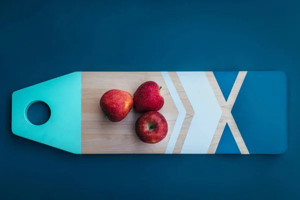 Trois pommes sur planche à découper — Photo