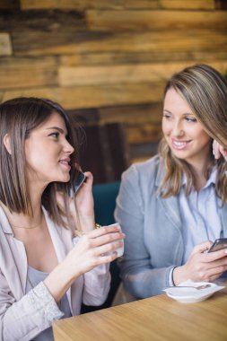Oturma ve akıllı telefonlar üzerinde konuşurken kızlar