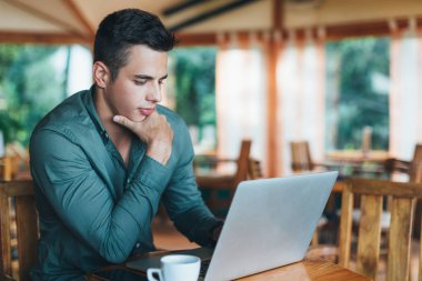 Oturma ve dizüstü bilgisayar kullanarak adam