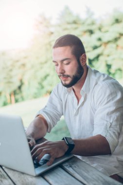 Oturma ve dizüstü bilgisayar kullanarak adam