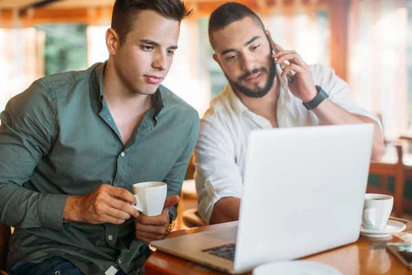 İki adam dizüstü bilgisayar kullanarak