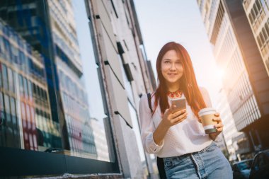 Sokakta cep telefonu olan genç bir kadın.