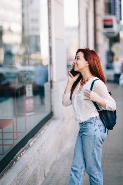 Sokakta cep telefonu olan genç bir kadın.