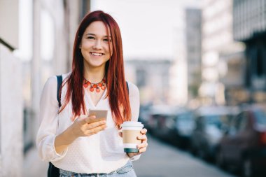 Sokakta cep telefonu olan genç bir kadın.