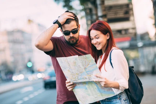 Casal de viajantes usando mapa na cidade — Fotografia de Stock