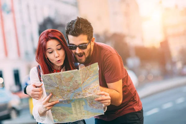 Casal de viajantes usando mapa na cidade — Fotografia de Stock