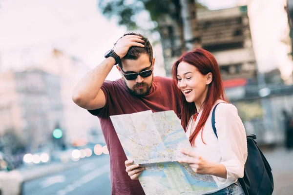 Casal de viajantes usando mapa na cidade — Fotografia de Stock