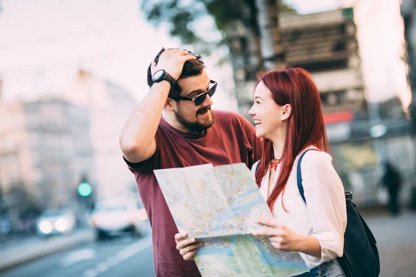 Casal de viajantes usando mapa na cidade — Fotografia de Stock